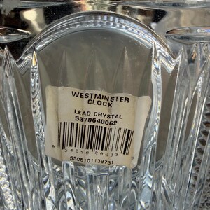 K&ouml;nnte beinhalten: Nahaufnahme eines transparenten Bleikristallobjekts mit strukturiertem, geometrischem Design. Ein Etikett lautet "Westminster Clock" und "Lead Crystal". Das Etikett enth&auml;lt auch einen Barcode und Seriennummern. Das Kristall reflektiert Licht.