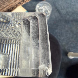K&ouml;nnte beinhalten: Ein klarer, rechteckiger Glasgegenstand mit vertikalen Linien und einer strukturierten Oberfl&auml;che. Der Gegenstand hat eine abgebrochene Ecke und scheint Teil eines gr&ouml;&szlig;eren St&uuml;cks zu sein. Das Glas ist leicht tr&uuml;b.