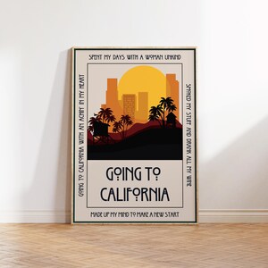 May include: A framed art print with a retro design. The artwork features a sunset over a silhouette of palm trees and buildings. The words "Going to California" are prominently displayed, with additional text around the border.