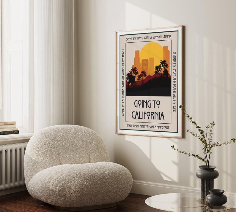 May include: A framed art print with a retro design featuring a California landscape with palm trees, a sunset, and the text "Going to California." The print has a beige background and a black border. The text includes the phrases "Spent my days with a woman unkind" and "Made up my mind to make a new start."