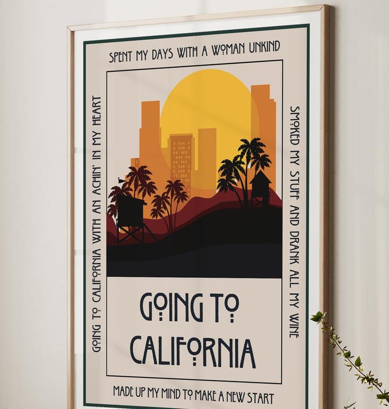 May include: A framed art print with a California theme. The artwork features a sunset over a city skyline with palm trees and the text "Going to California". The print has a beige background and a wooden frame.