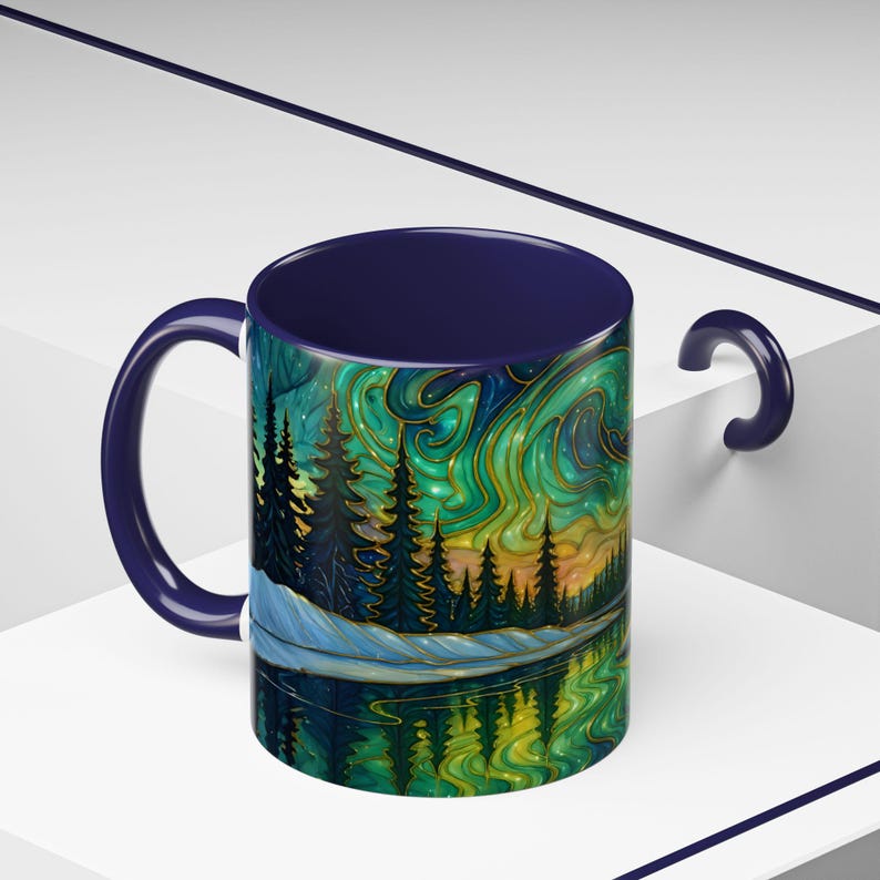 May include: A ceramic mug with a dark blue interior and handle. The exterior features a colorful landscape design with trees, a lake, and a swirling sky in shades of green, gold, and blue. The design is reflected in the water.