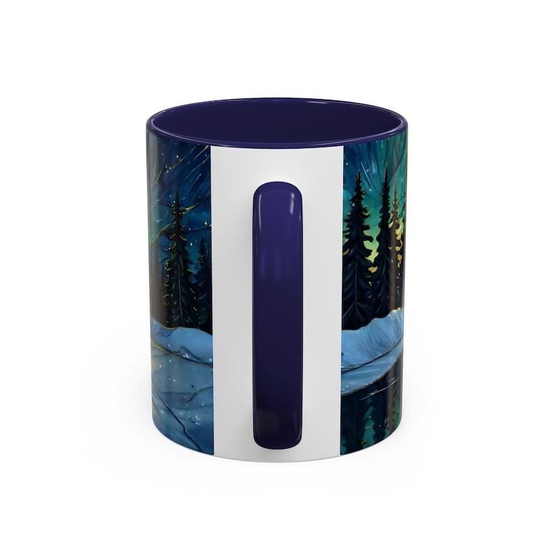 May include: White ceramic mug with a dark blue interior and handle. The exterior features a scenic illustration of a forest at night, with tall trees, a starry sky, and a body of water. The handle is a solid dark blue.