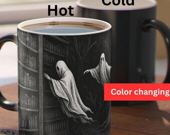 May include: Black color-changing mug with a spooky ghost design. The mug features a grayscale illustration of ghosts and a bookshelf. The text "Hot" and "Cold" are printed on the mug.