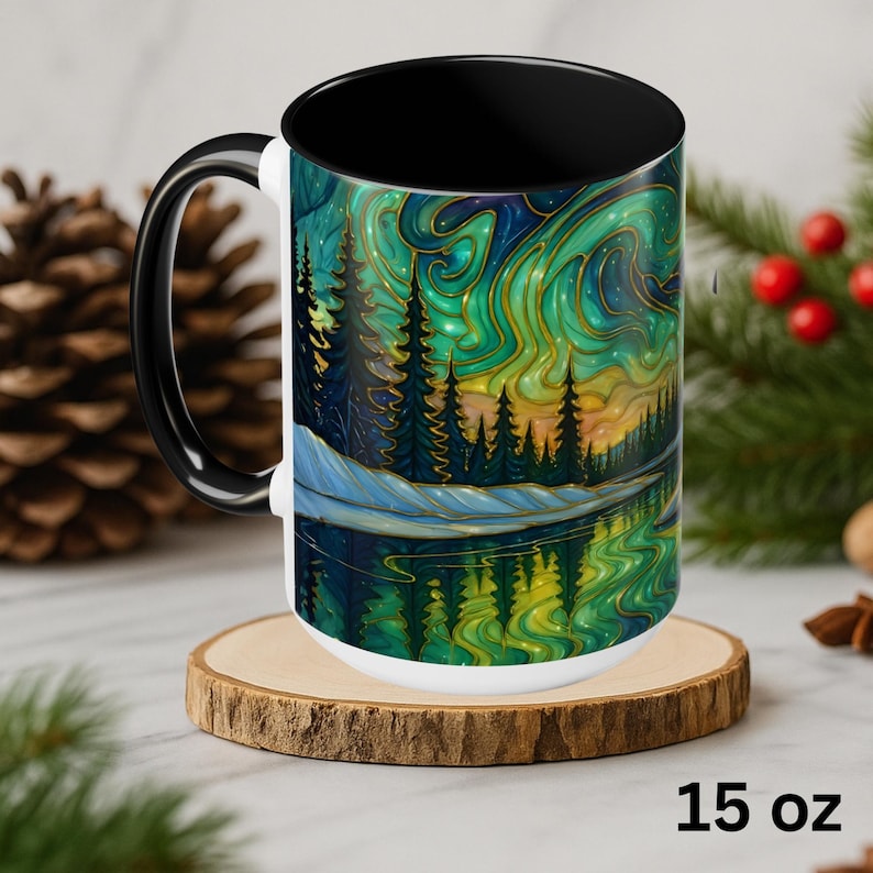 May include: A 15 oz ceramic mug with a black interior and handle, featuring a vibrant landscape design. The artwork depicts a forest scene with a lake, under a swirling green and gold aurora borealis. The mug sits on a wooden coaster.