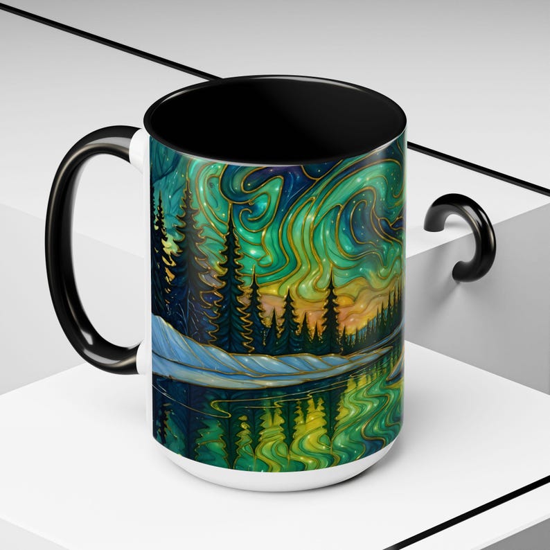 May include: A white ceramic mug with a black interior and handle. The mug features a vibrant, colorful illustration of a forest scene with a lake reflecting the aurora borealis in shades of green, blue, and gold.