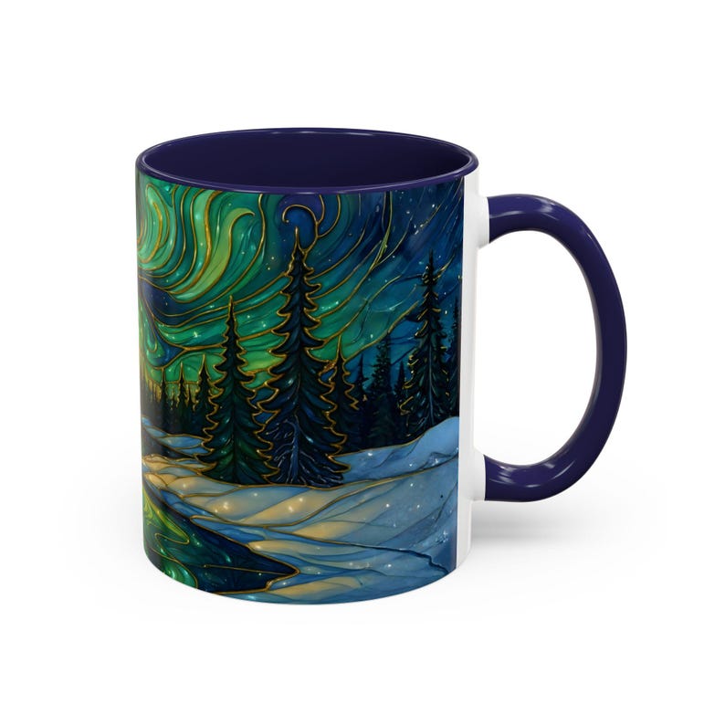 May include: White ceramic mug with a navy blue interior and handle. The mug features a colorful illustration of a winter landscape with a green and gold aurora borealis, evergreen trees, and a snowy ground. The design wraps around the mug.