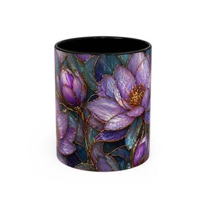 May include: A ceramic mug featuring a stained-glass floral design. The design showcases purple flowers with gold outlines against a dark teal background. The interior of the mug is black.