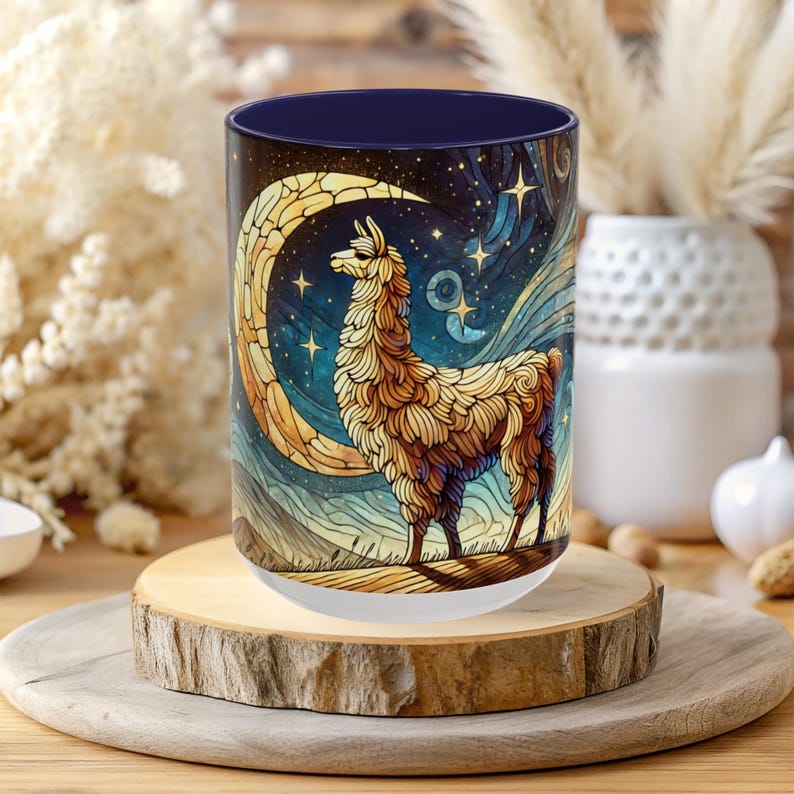 May include: A white ceramic mug with a blue rim features a colorful illustration of a llama standing under a crescent moon with stars in the background.
