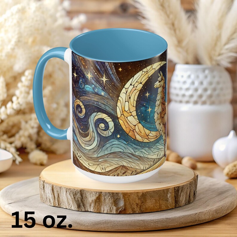 May include: A 15 ounce blue and white ceramic mug with a colorful stained glass design of a llama standing on a crescent moon. The design features a starry night sky and swirling clouds.