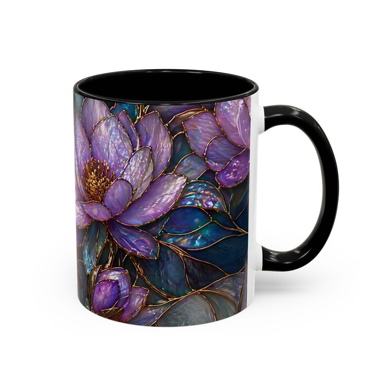 May include: White ceramic coffee mug with a black interior and handle. The mug features a floral design with purple, blue, and gold accents. The flowers are stylized with a stained glass effect.