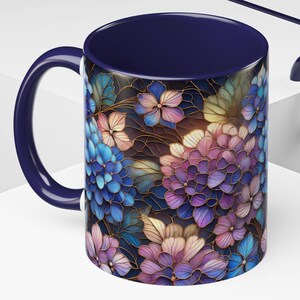 May include: A blue and purple floral mug with a dark blue rim and handle. The mug features a detailed design of hydrangeas with gold accents.