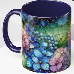 May include: A ceramic mug with a navy blue handle and interior. The exterior features a floral design with blue, pink, and green hydrangea-like flowers. The design has a stained glass effect with gold-colored outlines.