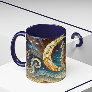 May include: A blue ceramic mug with a colorful illustration of a llama standing under a crescent moon with stars in the background.