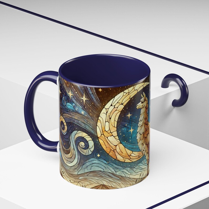May include: A blue ceramic mug with a colorful illustration of a llama standing under a crescent moon with stars in the background.