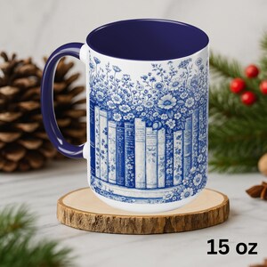 May include: A white ceramic mug with a blue interior and handle. The mug features a blue floral and book design. The mug is 15 oz.