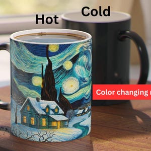 May include: A black color-changing mug with a white handle. The mug features a painting of a snowy landscape with a house and a starry night sky. The text "Hot" and "Cold" are printed on the mug, indicating the temperature-sensitive design. The text "Color changing mug" is printed below the mug.