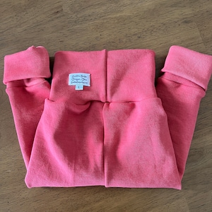 May include: Pink baby leggings with a white label that reads "Smilin' Baby Oregon, Ohio SmilinBaby.com L".