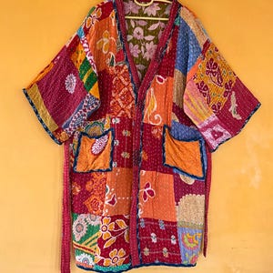 May include: A patchwork kimono-style jacket in a variety of colors, including red, orange, blue, and yellow. The jacket features a V-neck, two pockets, and a matching belt. The fabric appears to be quilted with intricate stitching.