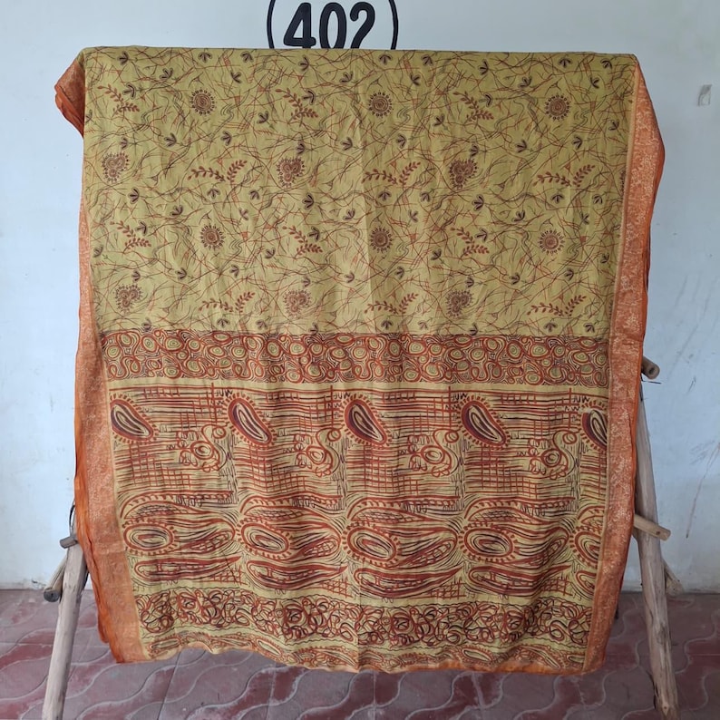 May include: A rectangular textile featuring a mustard yellow upper section with a dark brown fine-line floral pattern and a lower section with a bold dark brown paisley and geometric print, finished with a solid orange border on the sides.