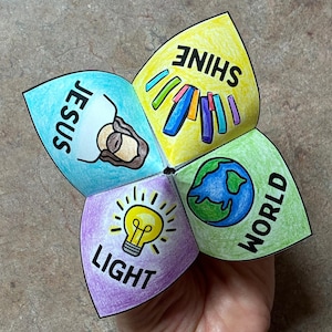 May include: A colorful paper fortune teller with the words "Jesus", "Shine", "World", and "Light" printed on the flaps. Each section features a corresponding illustration, including a lightbulb, a globe, and a depiction of Jesus.