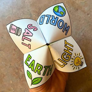 May include: A white paper fortune teller with the words "SALT", "WORLD", "EARTH", and "LIGHT" written on the flaps. Each flap has a corresponding illustration, including a salt shaker, a globe, a leaf, and a lightbulb.
