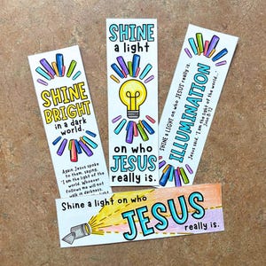 Op de afbeelding: Vier kleurrijke bladwijzers met religieuze thema's. De bladwijzers bevatten zinnen als "Shine Bright" en "Illumination", met illustraties van een gloeilamp en een schijnwerper. De tekst "Jezus" is prominent aanwezig.