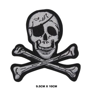 May include: A black and white embroidered patch of a skull and crossbones. The skull has a black eye patch and a toothy grin. The patch measures 9.5 inches by 10 inches.