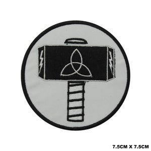 May include: Black and white embroidered iron-on patch of a hammer with a triquetra symbol. The patch is 7.5 inches by 7.5 inches.