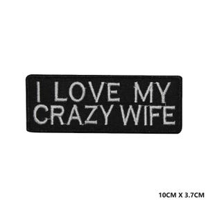 以下が含まれることがあります： 黒い刺繍のアイロン接着パッチで、白い文字で「I LOVE MY CRAZY WIFE」と書いてあります。パッチのサイズは10cm x 3.7cmです。