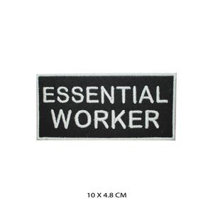 Op de afbeelding: Zwart-witte geborduurde patch met de tekst "ESSENTIAL WORKER" in witte letters op een zwarte achtergrond. De patch is 10 x 4,8 cm.