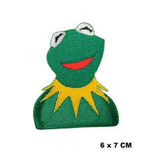Può includere: Toppa ricamata in feltro verde di una rana sorridente con feltro giallo intorno al collo. La toppa misura 6 x 7 centimetri.
