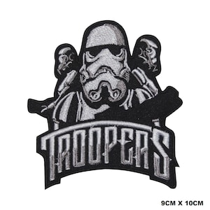 Può includere: Toppa ricamata in bianco e nero con un Stormtrooper di Star Wars e il testo "TROOPERS" sotto. La toppa misura 9 cm per 10 cm.