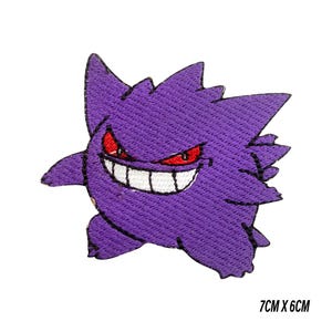May include: A purple embroidered patch of a cartoon ghost with a wide grin and red eyes. The patch measures approximately 7cm by 6cm and is set against a white background. The text "7CM X 6CM" is printed on the bottom right.