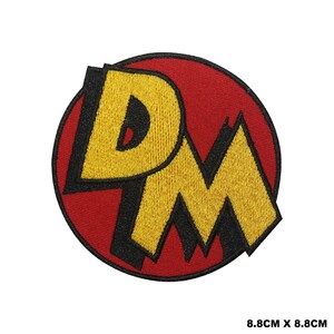 May include: A red and yellow embroidered patch with the letters "D.M." in a bold, cartoonish font. The patch is 8.8 inches by 8.8 inches.
