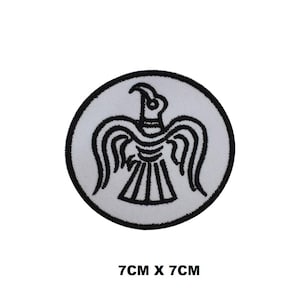 Könnte beinhalten: Weißer gestickter Aufnäher mit einem schwarzen, stilisierten Vogeldessin. Der Aufnäher ist 7 cm x 7 cm groß.