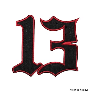Puede incluir: Parche de plancha negro con el número 13 en una fuente gótica con contorno rojo. El parche mide 9 cm por 10 cm.