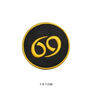 Könnte beinhalten: Ein gestickter schwarzer und goldener Aufnäher mit der Nummer 69 in einem Kreis. Der Aufnäher hat einen Durchmesser von 7 cm.