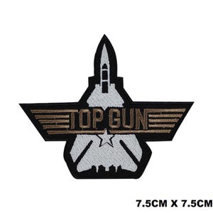 Op de afbeelding: Geborduurde strijkpatch met een wit gevechtsvliegtuig met bruine vleugels en de tekst "TOP GUN" in bruine letters. De patch is 7,5 cm bij 7,5 cm.