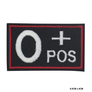 Puede incluir: Un parche negro bordado con un círculo blanco que contiene la letra "O" y un signo más blanco. El texto "POS" también está bordado en blanco. El parche tiene un borde rojo.