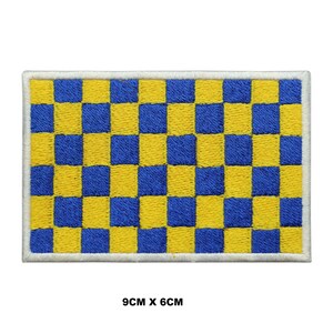 Pode incluir: Patch bordado retangular com um padrão xadrez amarelo e azul, emoldurado por uma borda branca. O patch mede 9 cm x 6 cm. O design é uma grade repetitiva de cores alternadas.