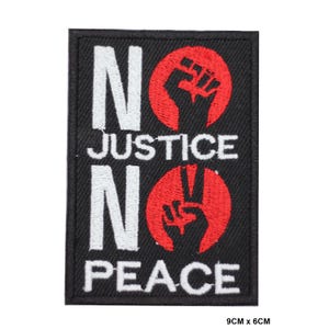 Puede incluir: Parche bordado negro con texto blanco que dice "No Justice No Peace" y dos puños rojos, uno levantado en puño y el otro en señal de paz. El parche mide 9 cm por 6 cm.