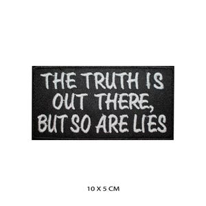 May include: Black embroidered patch with white text that reads "The truth is out there, but so are lies". The patch is 10 cm by 5 cm.