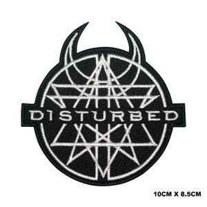 May include: Black and white embroidered patch featuring the band name "DISTURBED" in white lettering. The band's logo is a circle with a white geometric design and two horns at the top.