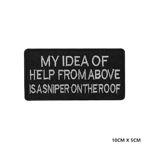May include: Black embroidered patch with white text that reads "My idea of help from above is a sniper on the roof". The patch is 10 cm by 5 cm.