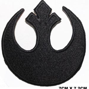 May include: Black embroidered patch of the Rebel Alliance symbol from Star Wars. The symbol is a white circle with a line through it, and two wings on either side. The patch is 7 inches by 7.2 inches.