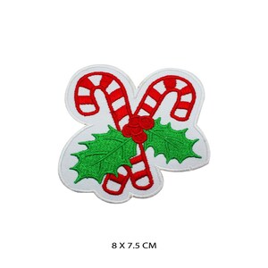 Può includere: Bastoncini di zucchero rossi e bianchi con foglie di agrifoglio verdi e bacche rosse. La toppa misura 8 x 7,5 cm.