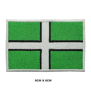 May include: Green and white embroidered patch with a white cross on a green background. The patch is 9 cm by 6 cm.