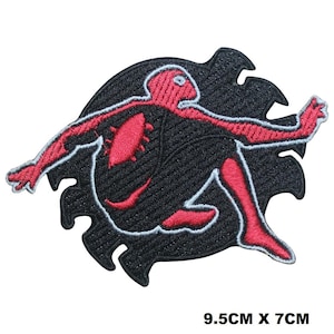 Könnte beinhalten: Roter und schwarzer gestickter Bügel-Patch mit einer Superheldenfigur in einer dynamischen Pose. Die Figur ist weiß umrandet und vor einem schwarzen Hintergrund mit einem gezackten Rand platziert.