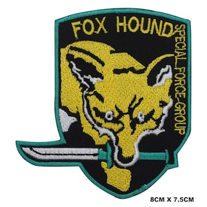 May include: A black and green embroidered patch with a yellow fox head and a silver knife. The patch says "FOX HOUND SPECIAL FORCE GROUP" and measures 8 inches by 7.5 inches.
